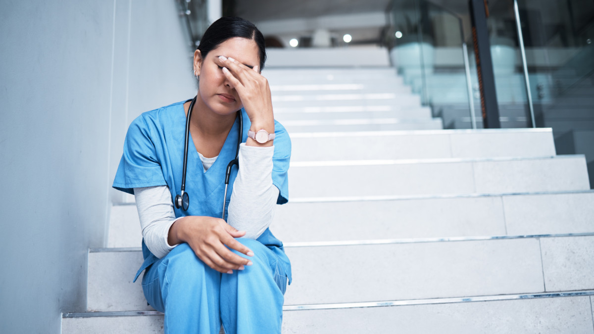 Female healthcare worker looking stressed while sitting on the stairs